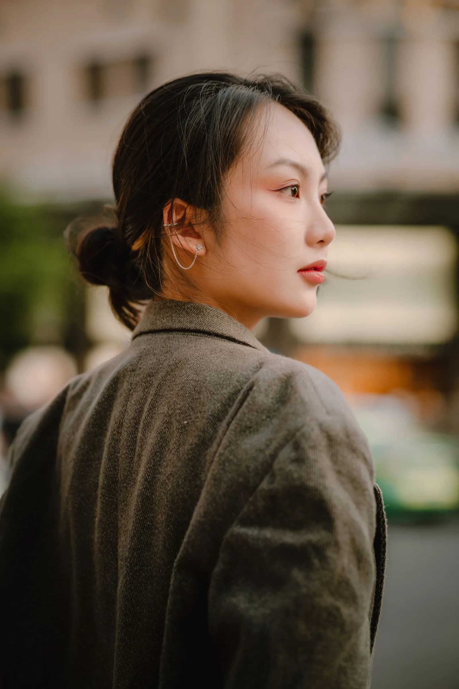 一位身穿外套的女性，在城市街角回望；生活场景示意
